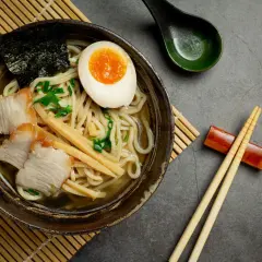 Miseczka aromatycznego ramenu z plastrami wieprzowiny, jajkiem na pół, bambusem i nori. Idealny przepis, jak ugotować ramen.
