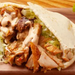 Pyszny kebab w bułce z soczystym mięsem, chrupiącą sałatą i kremowym sosem. Idealny na szybki posiłek.