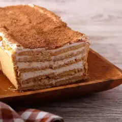 Tanie ciasto bez pieczenia z herbatnikami, przełożone kremem i posypane kakao. Idealne na szybki deser.