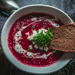 Aksamitny barszcz czerwony domowy, ozdobiony śmietaną, sezamem i świeżą natką. Idealny z kromką ciemnego chleba.