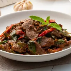 Pyszne wołowina po tajsku z bazylią i papryczką chili, podana w białej misce.