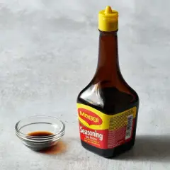 Butelka Maggi i miseczka z ciemnym płynem. Czy sos sojowy można zastąpić maggi?