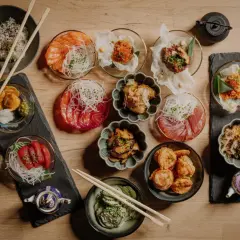 Pyszne sushi w Szczecinie czeka! Na stole różnorodne dania: łosoś, tuńczyk, krewetki, ryż i dodatki. Idealne na wspólne jedzenie.