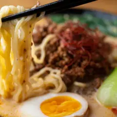 Jak zrobić ramen z zupki chińskiej? Miska pełna pysznego ramenu z makaronem, mięsem mielonym, jajkiem i warzywami.