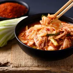 Miseczka pełna pikantnego kimchi, idealnego dodatku do wielu dań. Obok kapusta i chili.