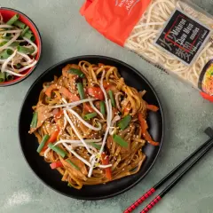 Gotowy makaron chow mein z warzywami i kiełkami fasoli. Obok opakowanie makaronu, gdzie kupić?