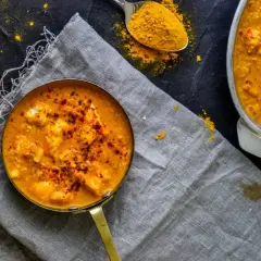 Aksamitny sos do butter masala, posypany papryką, obok łyżeczka kurkumy.