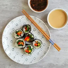 Roladki sushi z warzywami na talerzu, pałeczki i sosy. Tak przygotować nori do sushi, by było pyszne!