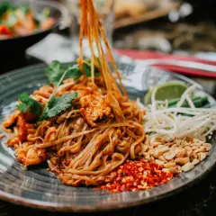 Pyszny pad thai z kurczakiem, orzeszkami, kiełkami i limonką. Tak jemy pad thai, dodając przyprawy do smaku.