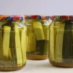 Słoiki z cukinią w zalewie słodko-kwaśnej z curry. Aromatyczne, domowe przetwory gotowe do spożycia.