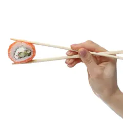 Dłoń trzymająca pałeczkami do sushi kawałek rolki sushi z łososiem i serkiem.