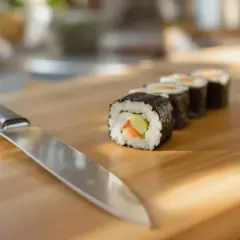Nóż i gotowe rolki sushi na desce. Dowiedz się, jak kroić ogórka do sushi, by uzyskać idealne kawałki.