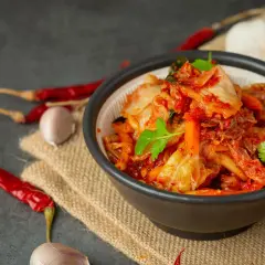Miseczka z kimchi, obok suszone papryczki chili i czosnek.