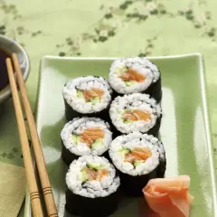 Siedem kawałków sushi z łososiem i ogórkiem na zielonym talerzu. Zastanawiasz się, ile kalorii ma sushi z łososiem?