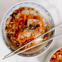 Miseczka ryżu z pikantnym kimchi, posypana sezamem i ziołami. Czy kimchi jest zdrowe? Tak, to fermentowany przysmak pełen probiotyków.