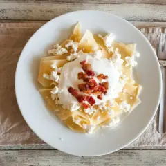 Pyszny makaron na słodko z twarogiem, śmietaną i skwarkami. Idealny na deser lub śniadanie.