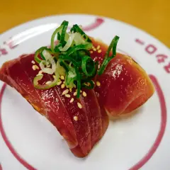 Dwa kawałki tuńczyka na ryżu, posypane sezamem i szczypiorkiem. Zastanawiasz się, ile kosztuje sushi w Japonii?