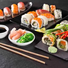 Różnorodne sushi i rolki z łososiem, awokado i warzywami, podane z imbirem, wodorostami i sosem sojowym.