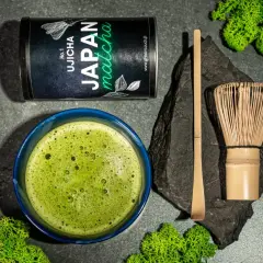 Zestaw do parzenia matcha: puszka z zieloną herbatą, spieniony napój w miseczce, bambusowa miotełka (chasen) i łopatka (chashaku).