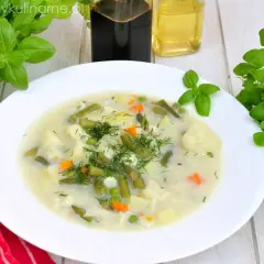 Aromatyczna, tradycyjna zupa jarzynowa z ziemniakami, fasolką szparagową, kalafiorem i groszkiem, udekorowana świeżym koperkiem.