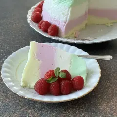 Kolorowy jogurtowiec z jogurtu greckiego, udekorowany malinami i miętą, na talerzyku.