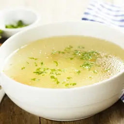 Aromaticzny rosół z perliczki, podany z chlebem i natką pietruszki. Idealny na chłodne dni.