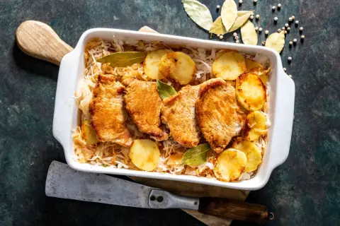 Aromaticzny schab w kapuście kiszonej z ziemniakami i liśćmi laurowymi, gotowy do podania.