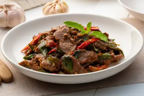 Pyszne wołowina po tajsku z bazylią i papryczką chili, podana w białej misce.