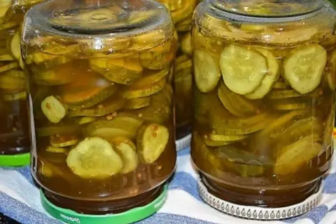 Słoiki pełne plastrów ogórków z curry, gotowe do spiżarni.