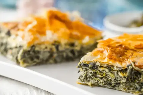 Chrupiąca spanakopita z warstwami ciasta filo i zielonym nadzieniem ze szpinaku i sera feta.