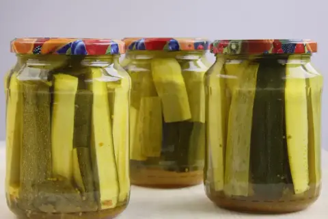 Słoiki z cukinią w zalewie słodko-kwaśnej z curry. Aromatyczne, domowe przetwory gotowe do spożycia.