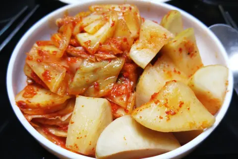 Pikantne kimchi w białej misce. Zastanawiasz się, jak długo przechowywać kimchi? To danie jest gotowe do spożycia!