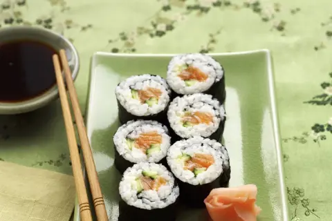 Siedem kawałków sushi z łososiem i ogórkiem na zielonym talerzu. Zastanawiasz się, ile kalorii ma sushi z łososiem?