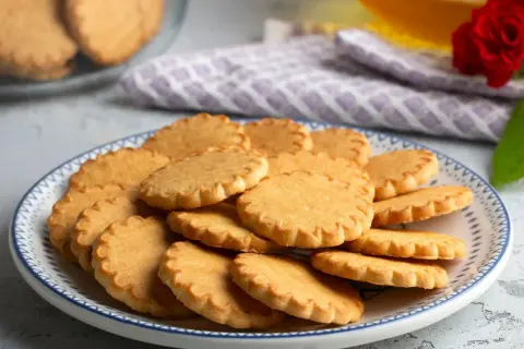 Stos szybkich kruchych ciasteczek na talerzu z niebieskim wzorem. Idealne na popołudniową herbatę.
