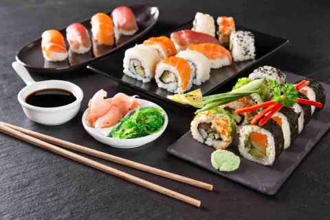 Różnorodne sushi i rolki z łososiem, awokado i warzywami, podane z imbirem, wodorostami i sosem sojowym.