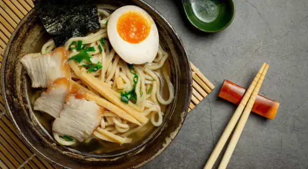 Miseczka aromatycznego ramenu z plastrami wieprzowiny, jajkiem na pół, bambusem i nori. Idealny przepis, jak ugotować ramen.