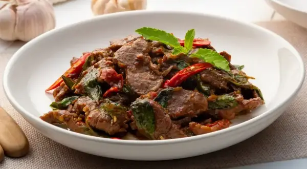 Pyszne wołowina po tajsku z bazylią i papryczką chili, podana w białej misce.