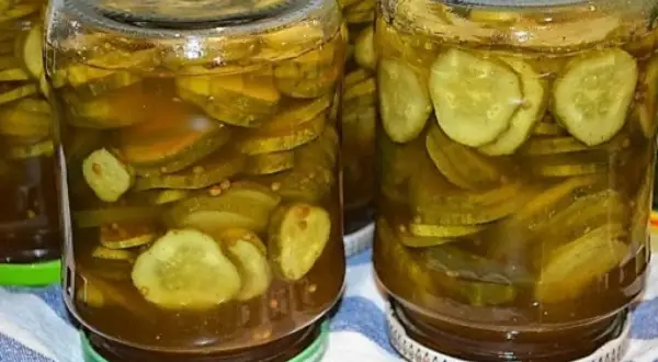 Słoiki pełne plastrów ogórków z curry, gotowe do spiżarni.
