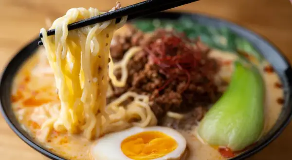 Jak zrobić ramen z zupki chińskiej? Miska pełna pysznego ramenu z makaronem, mięsem mielonym, jajkiem i warzywami.