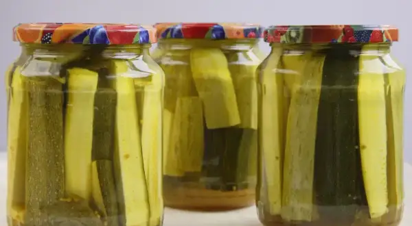 Słoiki z cukinią w zalewie słodko-kwaśnej z curry. Aromatyczne, domowe przetwory gotowe do spożycia.