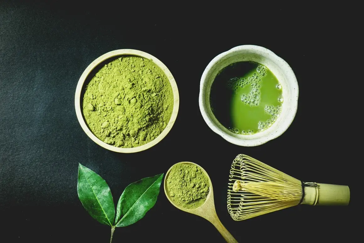 Miska z zielonym proszkiem matcha, filiżanka napoju, drewniana łyżka i bambusowa miotełka.