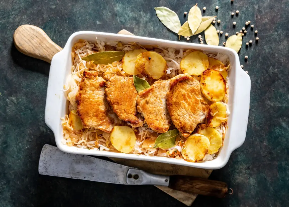 Aromaticzny schab w kapuście kiszonej z ziemniakami i liśćmi laurowymi, gotowy do podania.