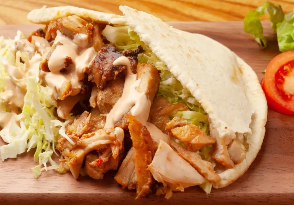Pyszny kebab w bułce z soczystym mięsem, chrupiącą sałatą i kremowym sosem. Idealny na szybki posiłek.