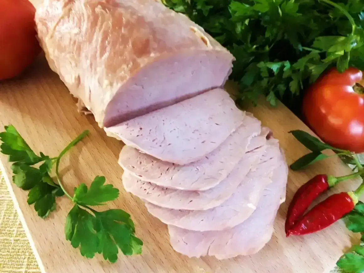 Pokrojony schab gotowany 2 razy po 10 minut, podany z pomidorami, papryczkami chili i natką pietruszki na desce.