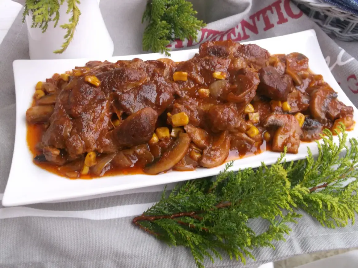 Karkówka pieczona w plastrach z cebulą i pieczarkami, polana sosem z dodatkiem kukurydzy. Pyszne danie, które zachwyci każdego.