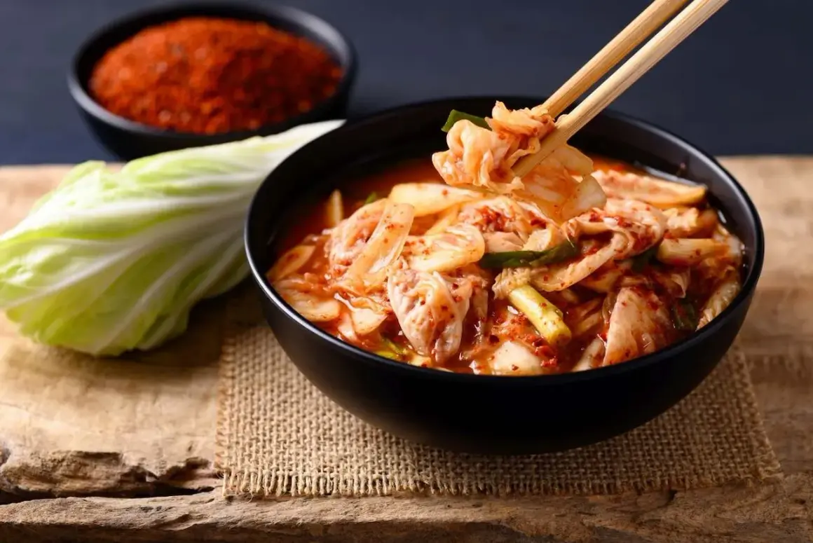 Miseczka pełna pikantnego kimchi, idealnego dodatku do wielu dań. Obok kapusta i chili.