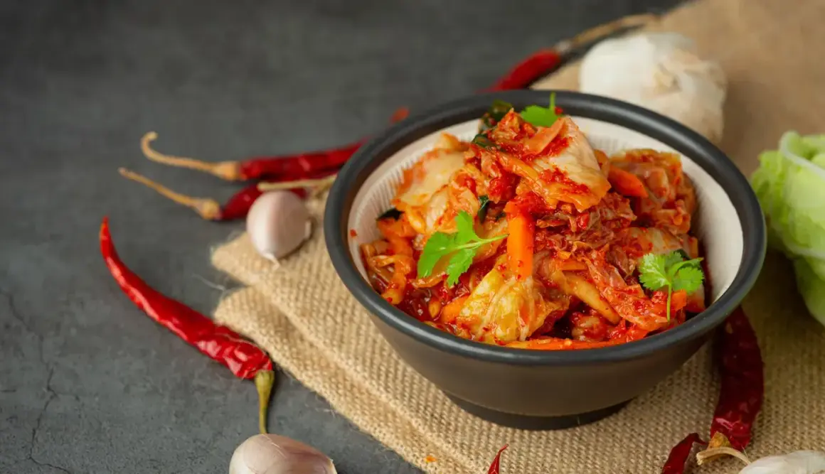 Miseczka z kimchi, obok suszone papryczki chili i czosnek.