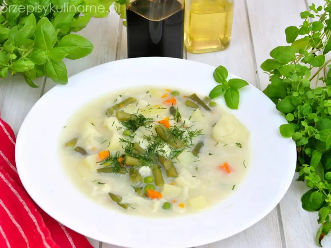 Aromatyczna, tradycyjna zupa jarzynowa z ziemniakami, fasolką szparagową, kalafiorem i groszkiem, udekorowana świeżym koperkiem.