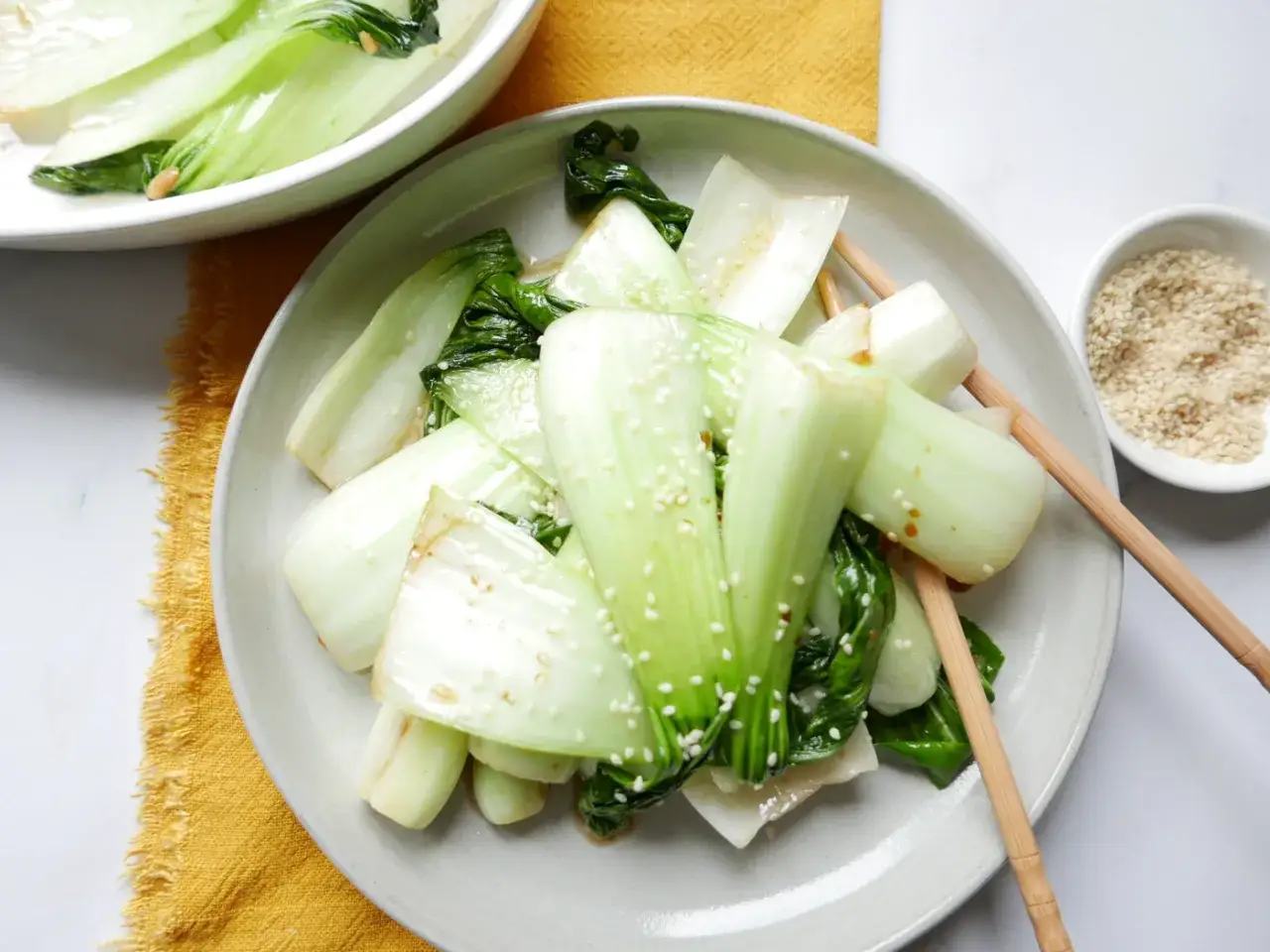 Pyszne kapusta pak choi przepisy na talerzu, posypane sezamem. Gotowe do podania z pałeczkami.