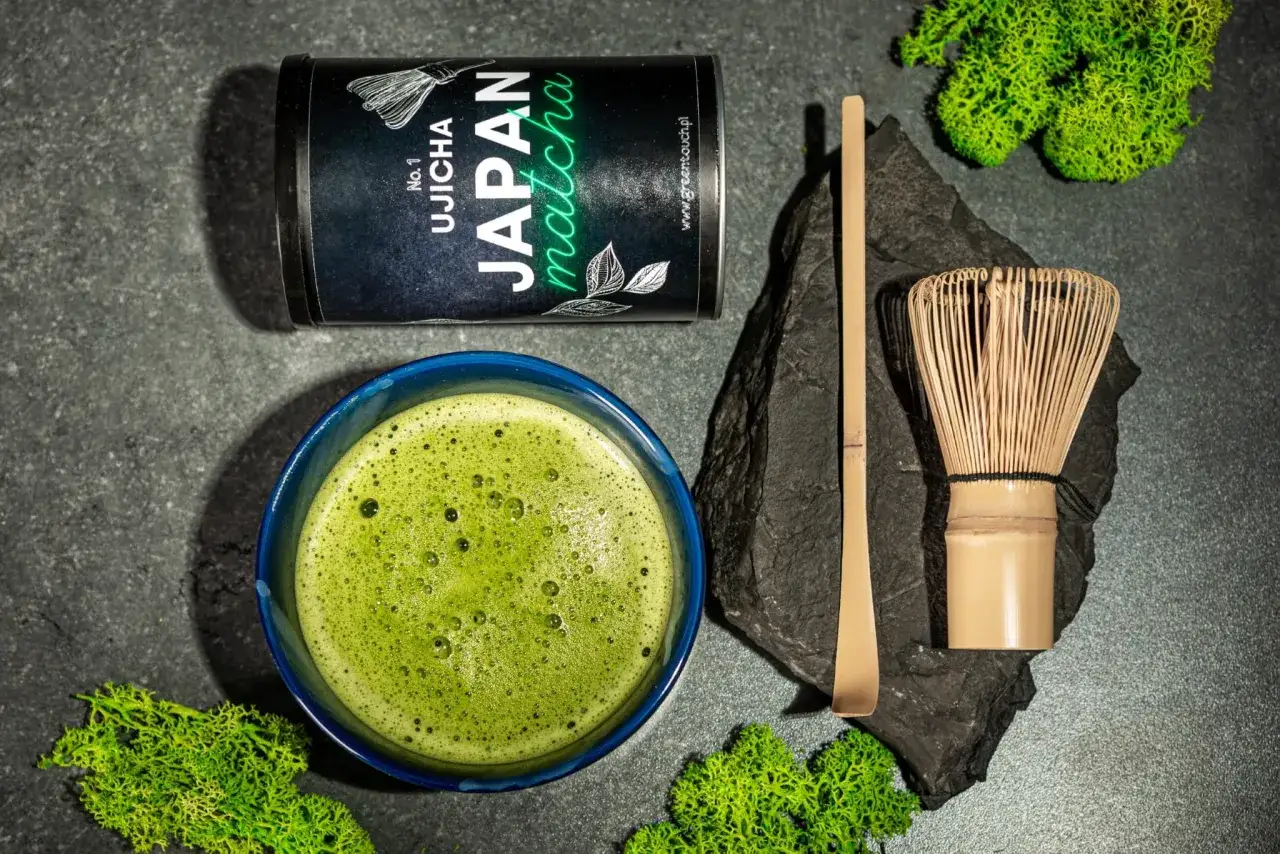 Puszka japońskiej matcha, spieniony napój w niebieskiej miseczce, bambusowa miotełka i łopatka. Idealny zestaw, by dowiedzieć się, jak pić matcha.